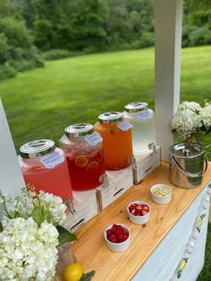 some drinks are sitting on a table with flowers and lemons in the vases