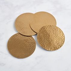 three brass coasters sitting on top of a white table