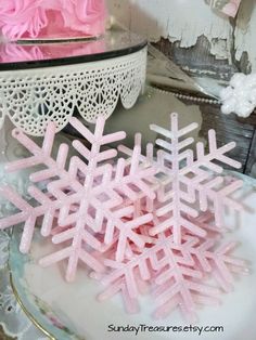 pink snowflakes are sitting on a plate next to a lace doily