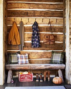 a wooden bench sitting in the middle of a room next to a wall with coats hanging on it