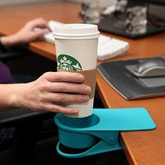 a person is holding a coffee cup in their hand while sitting at a computer desk