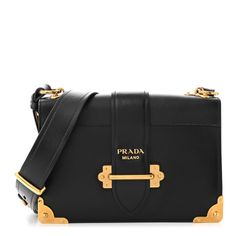 This is an authentic PRADA City Calf Saffiano Large Cahier Bag in Black. This stylish shoulder bag is crafted of calfskin leather in black. The bag features black textured leather on the top, an adjustable black leather shoulder strap, and brass hardware including corner plates and a closure. The top opens to a black leather interior with patch pockets. Prada Cahier Bag, Stylish Shoulder Bag, Black Textures, Leather Interior, Leather Projects, Luxury Items, Prada Bag, Patch Pocket, Calf Skin