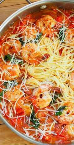 a pan filled with pasta and shrimp on top of a wooden table