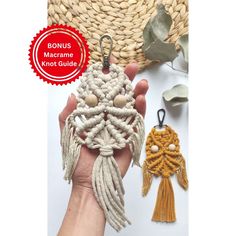 a hand holding a small crochet keychain with two tassels attached to it