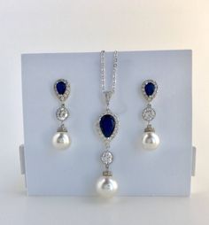 #Classic pearl bridal necklace and pendant set with rhodium plated brass peg and bail. Necklace features a halo blue sapphire crystal teardrop pendant with a 12mm Swarovski single pearl drop that dangles from round rhodium plated cubic zirconia connector and bail. Length of the rhodium plated chain is 18 inches and comes with 2 inches extender and lobster clasp. For matching earrings click: https://www.etsy.com/listing/578469918/blue-bridal-earrings-sapphire-wedding?ref=shop_home_active_3 For co Blue Wedding Necklace With Accent Stones, Elegant Sapphire Bridal Necklace In Cubic Zirconia, Elegant Blue Sapphire Bridal Necklace, Sapphire Crystal Bridal Necklace Gift, Sapphire Cubic Zirconia Bridal Necklace, Rhodium Jewelry, Blue Bridal Earrings, Bridal Pearl Necklace, Sapphire Wedding