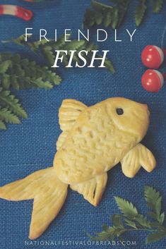 a yellow fish sitting on top of a blue cloth next to green leaves and berries