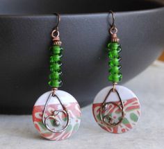 A different twist to your usual holiday earrings featuring green and reddish coral enamel charms. The abstract pattern on the enamels reminds me of a tree branch. I have paired them with spiraling green lampwork beads and copper beads. I have accented them with teardrop shaped copper components. These unique earrings measure 2 1/2 inches in total length and hang on niobium earring hooks. All pieces come boxed ready for gift giving or keeping for yourself. Return to shop: bstrung.etsy.com More li Bohemian Green Jewelry For Holiday, Green Wire Wrapped Beaded Earrings For Gift, Green Wire Wrapped Beaded Earrings As Gift, Festive Green Nickel-free Earrings, Green Spiral Earrings As Gift, Blue And White Earrings, Lampwork Bead Earrings, Bohemian Christmas, Lampwork Earring