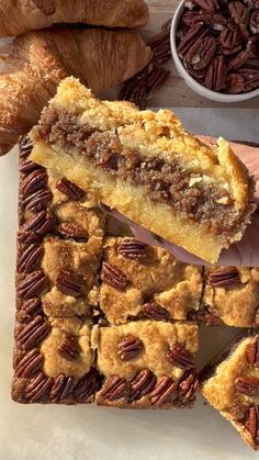 a person holding up a piece of pecan pie on top of a cutting board