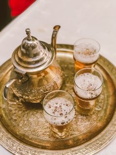 three glasses and a tea pot on a tray