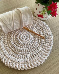 a white crochet placemat with yarn on it next to a potted plant