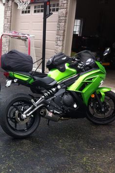 a green motorcycle parked in front of a garage