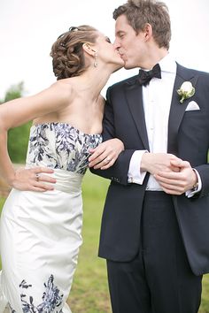 a bride and groom kissing each other outside