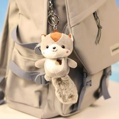 a small stuffed animal hanging from the side of a backpack with a keychain attached to it