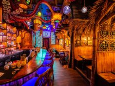 the interior of a bar with colorful lights and decorations on the walls, along with wooden tables and chairs