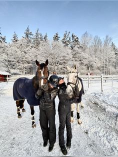 two women are standing in the snow with their horses and one is wearing a black jacket