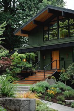 a green house with stairs leading up to the front door and trees in the background