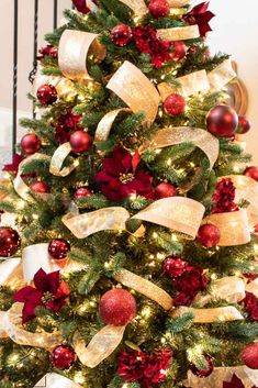 a christmas tree decorated with red and gold ribbons, bows, and baubles