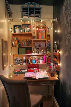 a desk and chair in a small room with lights on the shelves above it,