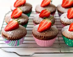 chocolate cupcakes with powdered sugar and fresh strawberries on top are ready to be eaten