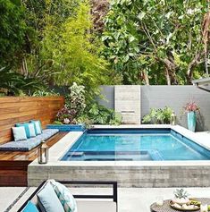 an outdoor pool surrounded by greenery and furniture in the middle of a patio area