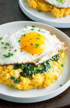 two white plates topped with eggs and spinach