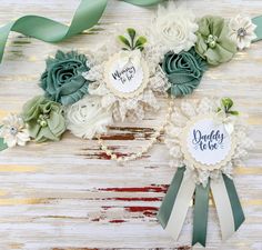 three paper flowers with green ribbons on top of each one and the words daddy to be written on them