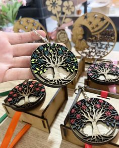 the tree of life keychains are being held by someone's hand on top of a table