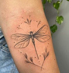 a small dragonfly tattoo on the arm