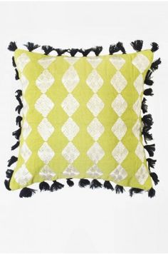 a green and white pillow with black tassels