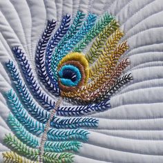 a close up view of a quilted piece with colorful feathers and leaves on it