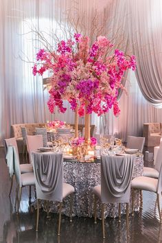 a fancy table with pink flowers on it and silver linens around the tables for seating