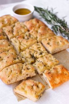 bread cut into squares and sitting on a table next to a small bowl of dipping sauce