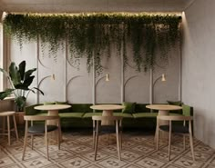 a living room with green couches and plants on the wall above them, along with tables and chairs