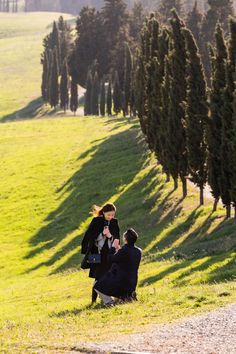 two people sitting in the grass near trees