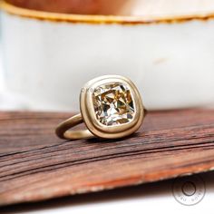 a close up of a gold ring with a diamond in the center on a wooden surface