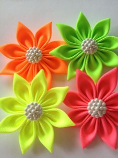 four different colored flowers on a white surface