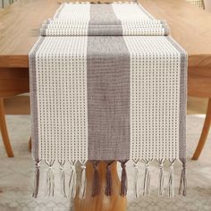 a table topped with a white and gray striped table runner next to a wooden table