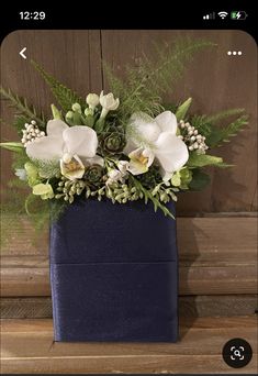 a blue vase with white flowers and greenery