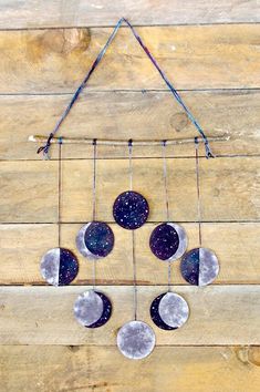 a wind chime hanging on the side of a wooden wall with moon phases attached to it