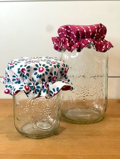 two mason jars with red, white and blue fabric on them sitting on a table