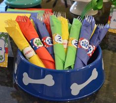 a blue bowl filled with lots of different colored napkins next to a sign that says wipe your paws