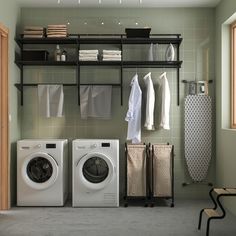 a washer and dryer in a room with clothes hanging on the rack next to it