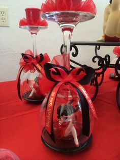 two wine goblets with figurines in them on a red table cloth