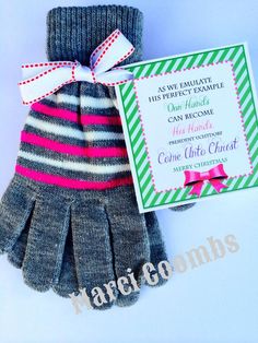 a pair of gloves with a pink and green striped bow on the wrist, next to a card