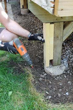 a person is using a power drill to fix a hole in the ground near a bench