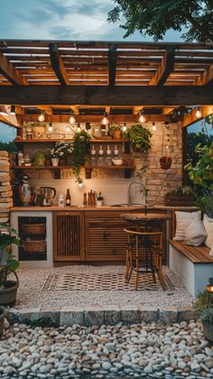 an outdoor kitchen is lit up with lights and potted plants on the counter top