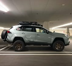 a light blue jeep parked in a parking garage with its roof rack mounted on top