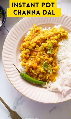 a white plate topped with rice and curry next to a green pepper on top of it