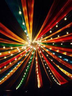 an image of colorful lights in the night sky with long ribbons hanging from it's ceiling