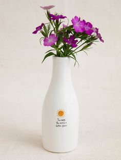 a white vase with purple flowers in it